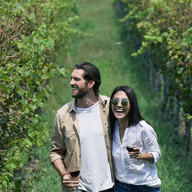 couple strolling in a plantation holding wine glass