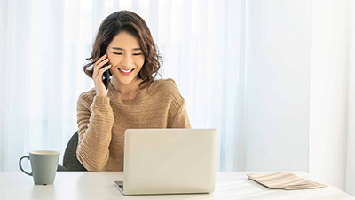 lady working on her laptop while talking on her cellphone